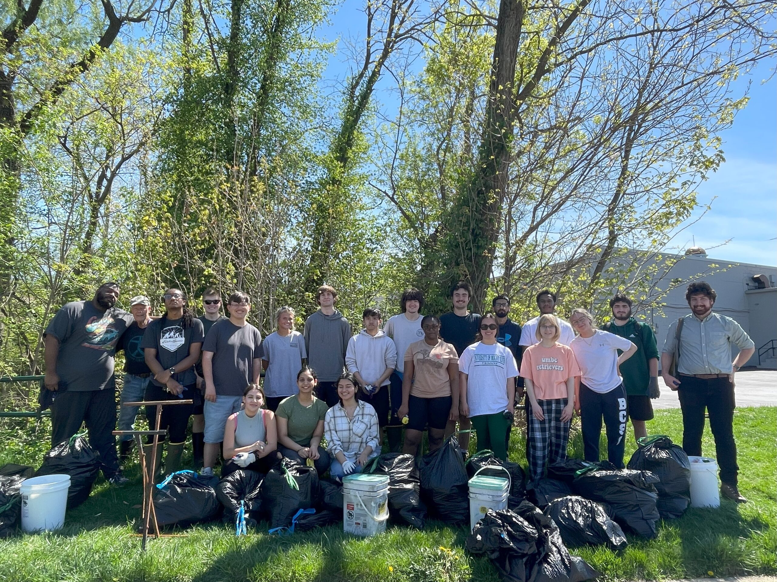 A group of volunteers stand with the trash they collected during a stream cleanup